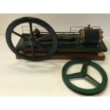 A bespoke stationary steam engine with green painted base and over-sized black painted fly wheel