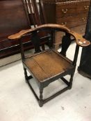 An 18th Century oak yoke back corner chair with plank seat on turned legs united by stretchers,