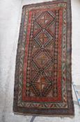 A Caucasian rug with repeating lozenge medallions in green, terracotta and blue,
