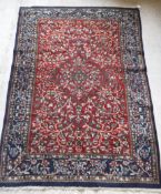 A Persian rug with centre medallion on a floral and foliate decorated red ground,