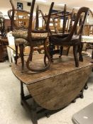 An oak drop-leaf table together with fou