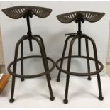 A pair of iron tractor seat stools, the seats inscribed "Wm Doyle & Co.