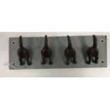 A set of four modern cast iron dog rear end coat hooks on a slate mount