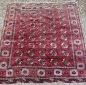 A Bokhara carpet with all over elephant foot medallion decoration on a red ground,