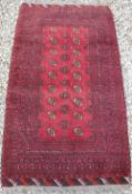 A Turkamen rug with repeating elephant foot medallions on a red ground,