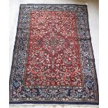 A Persian rug with centre medallion on a floral and foliate decorated red ground,