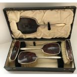 A George V silver and tortoiseshell mounted dressing table brush set comprising mirror,