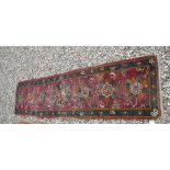 A Turkish runner, the central panel set with repeating stylised flower head motifs on a pink ground,