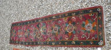 A Turkish runner, the central panel set with repeating stylised flower head motifs on a pink ground,