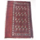 A Bokhara Juval rug with all over stylised medallion decoration on a red ground,