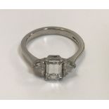 A platinum dress ring with central emerald cut diamond (approx 1.