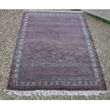 A Persian carpet, the central panel set with repeating motifs on a pink ground,