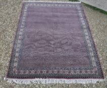 A Persian carpet, the central panel set with repeating motifs on a pink ground,