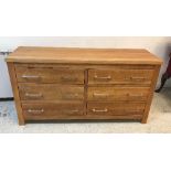 A modern teak bank of six drawers with polished metal handles, raised on stile supports,