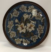 A framed and glazed beadwork panel, the blue ground set with floral sprays,