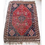 A Shiraz rug with lozenge shaped medallion on a red ground with all over geometric floral design,