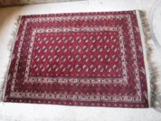 A Bokhara rug with repeating elephant foot medallions on a red ground,