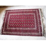 A Bokhara rug with repeating elephant foot medallions on a red ground,