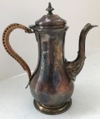 A George III silver coffee pot of baluster form with caned handle and raised on circular stepped