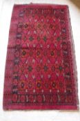 A Bokhara saddle rug with repeating stylised lozenge flower head and foliate medallions on a red