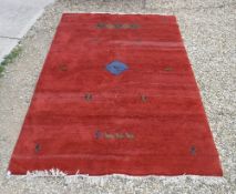 A Gabbeh carpet, the plain red ground sparsely decorated with animal, insect and figural motifs,