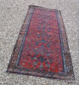 A Hamadan runner, the central panel set with repeating design on a red ground,