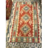 A pair of Kelim rugs with stylised diamond decoration of red, blue,