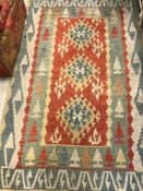 A pair of Kelim rugs with stylised diamond decoration of red, blue,