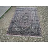 An Oriental carpet, the central panel set with floral decorated lozenge shaped medallion on a blue,