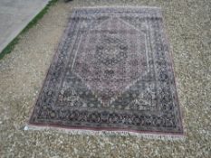 An Oriental carpet, the central panel set with floral decorated lozenge shaped medallion on a blue,