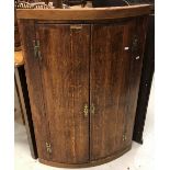 A George III oak and cross-banded North Country bow fronted hanging corner cupboard,