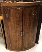A George III oak and cross-banded North Country bow fronted hanging corner cupboard,