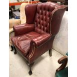 An early to mid 20th Century buttoned red leather wing back scroll armchair on cabriole legs to