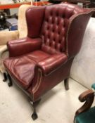 An early to mid 20th Century buttoned red leather wing back scroll armchair on cabriole legs to