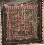 An Indian needlework panel with stylised flower head decoration to centre and applied mirrored