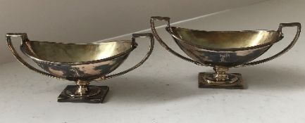 A pair of Victorian silver boat shaped salts with armoured arm holding sheath of corn armorial to