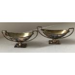 A pair of Victorian silver boat shaped salts with armoured arm holding sheath of corn armorial to