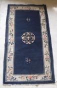 A circa 1950 Chinese rug, the central panel set with floral decorated medallion on a blue ground,