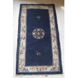 A circa 1950 Chinese rug, the central panel set with floral decorated medallion on a blue ground,