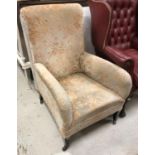 An Edwardian upholstered armchair on square tapered legs to castors,