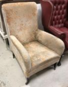 An Edwardian upholstered armchair on square tapered legs to castors,