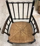 A circa 1900 ebonised beech framed Sussex type armchair after a design by William Morris with rush