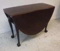 A circa 1900 oval mahogany drop leaf dining table on cabriole legs to claw and ball feet in the