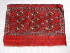 A Bokhara Juval rug with repeating medallion decoration on a scarlet ground,