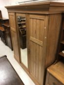 A Victorian ash triple wardrobe with central mirrored door enclosing a linen shelf (two missing)