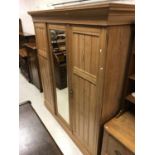 A Victorian ash triple wardrobe with central mirrored door enclosing a linen shelf (two missing)