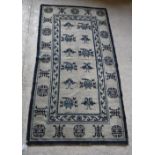 A Chinese rug, the central panel set with repeating Oriental floral motifs on a cream ground,