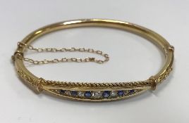 A gold hinged bangle with ropework banded arrangement of seven graduated old cut diamonds (approx 0.