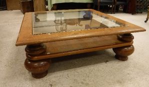 A mid 20th Century mahogany framed glass top coffee table on heavy baluster turned squat supports