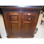 A George III oak and cross-banded corner cupboard, the two doors enclosing three shaped shelves,